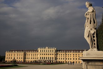 Schonnbrunn Palace. Exterior with statue of standing figure in foreground beneath grey stormy sky.