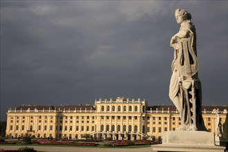 Schonnbrunn Palace. Exterior with statue of standing figure in foreground beneath grey stormy sky.
