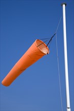 Orange wind-sock blowing in the wind indicating wind direction and strength. Photo : Paul Seheult