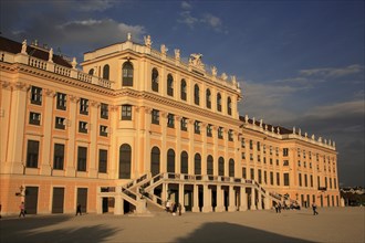 Schonnbrunn Palace. Part view of exterior facade with tourist visitors in courtyard in foreground.