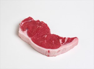 Slice of raw uncooked sirloin steak on a white background. Photo : Paul Seheult