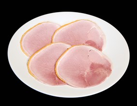 Slices of cured ham on a round white plate on a black background. Photo : Paul Seheult