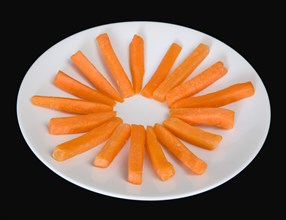 Slices of raw uncooked carrot on a white plate against a black background. Photo: Paul Seheult