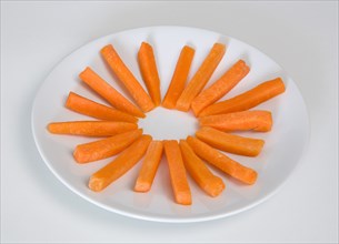Slices of raw uncooked carrot on round white plate against a white background. Photo: Paul Seheult