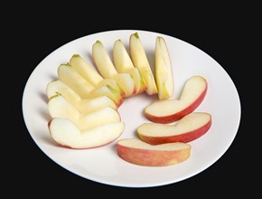 Slices of ripe apple on a white plate against a black background. Photo : Paul Seheult