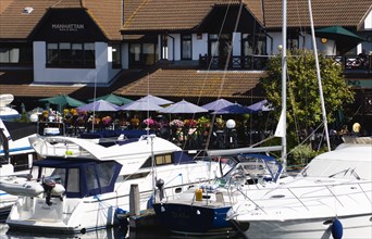 Port Solent Boats moored in the marina with people sitting at restaurant tables beyond. Photo: Paul