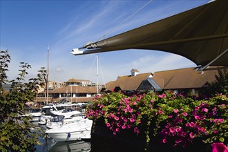 Port Solent Boats moored in the marina with people sitting at restaurant tables beyond beside a pub