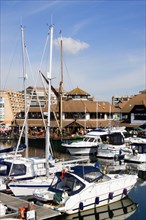 Port Solent Boats moored in the marina with people sitting at restaurant tables beyond beside a pub