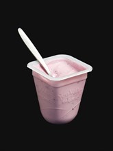 Yeo Valley probiotic blueberry fruit yogurt with spoon in pot against a black background. Photo: