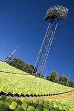 Olympic Stadium. Angled view across green seating of the stadium with floodlight and part view of