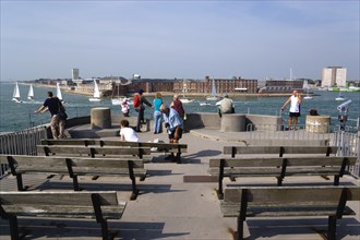 Tourists and seats on the top of The Round Tower in Old Portsmouth and yachts passing through the