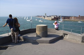 Tourists on the top of The Round Tower in Old Portsmouth and yachts passing through the entrance to