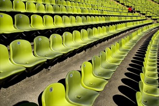 Olympic Stadium. Curved section of bright green seating in the stadium with couple seated at far