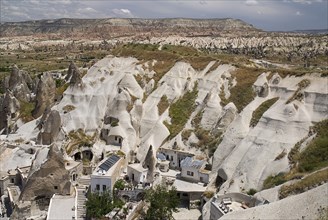 Looking down on a cave hotel built into the white tufa rock with the Red Valley behind. Photo :