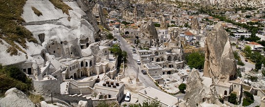 Cave hotel built into white tufa rock of hillside with part view of the town beyond. Photo : Hugh