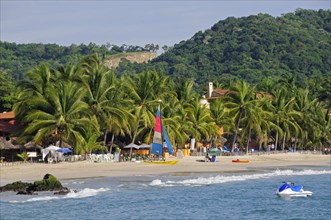 Mexico, Guerrero, Zihuatanejo, View across water towards Playa la Ropa sandy beach lined with lush