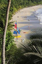 Mexico, Guerrero, Zihuatanejo, View onto Playa la Ropa with a colourful sailboat on sandy beach