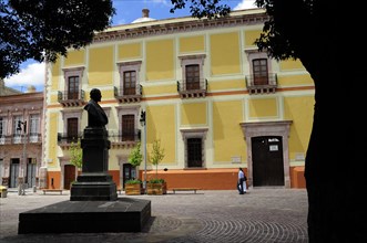Mexico, Bajio, Zacatecas, Plaza San Augustin. Yellow painted building and statue. 
Photo : Nick
