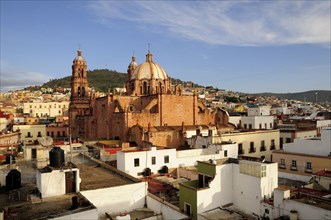 Mexico, Bajio, Zacatecas, View across flat rooftops of houses towards Cathedral. 
Photo : Nick