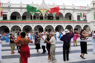 Mexico, Veracruz, Veracruz, Couples dancing in the Zocalo with facade of government buildings