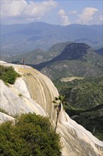 Mexico, Oaxaca, Hierve el Agua, Tourist standing on limestone cliff looking out over surrounding