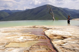 Mexico, Oaxaca, Hierve el Agua, Female tourist standing in limestone pool with view towards