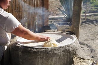 Mexico, Oaxaca, Woman making tortillas outside on traditional comal griddle. 
Photo : Nick Bonetti
