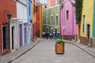Mexico, Bajio, Guanajuato, Paved street lined by colourfully painted houses group of four people