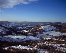 England, Derbyshire, Hathersage, View westwards over snow covered moorland landscape and fields