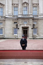 England, London, Westminster Buckingham Palace exterior with Police guard at the entrance. 
Photo