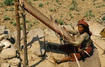 Nepal, East, Gudel, Woman sitting on ground to weave textile on hand loom. 
Photo : Chris Beall