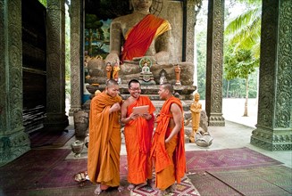 Cambodia, Siem Reap, Angkor Thom, Buddhist monks laughing at a picture on a digital reading tablet.