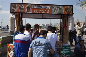 Turkey, Istanbul, Eminonu Ice cream vendor outside the New Mosque with young men waiting to be