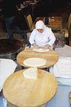 Turkey, Istanbul, Sultanahmet woman rolling out bread dough in restaurant. 
Photo : Stephen