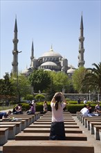 Turkey, Istanbul, Sultanahmet Camii Blue Mosque with tourist taking picture on her camera phone.