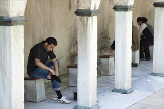 Turkey, Istanbul, Sultanahmet Camii Blue Mosque man preparing to wash feet before worship. 
Photo