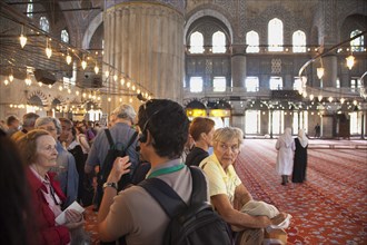 Turkey, Istanbul, Sultanahmet Camii Blue Mosque interior with guided tour group listening on