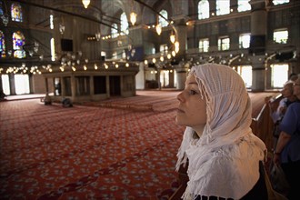 Turkey, Istanbul, Sultanahmet Camii Blue Mosque interior. Female visitor wearing headscarf looking