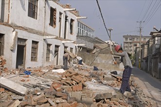 China, Jiangsu, Qidong, Demolition workers using hammers with flexible handles to demolish old