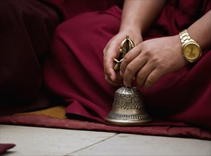 Buddhist Monk playing musical bell in a Losar ceremony, Sikkim, India