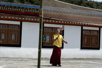 Buddhist monk playing badminton at a monastery, Sikkim, India