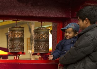 Father and son devotees turning prayer wheels at a Buddhist  Monastery, Sikkim, India