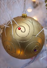 Festivals, Christmas, Decorations gold coloured bauble with white tinsel and fairy lights. 
Photo