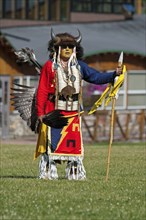 Blackfoot dancer in a buffalo headdress and sunglasses wearing a porcupine quill breastplate and holding a spear and feather fan at the Blackfoot Arts & Heritage Festival Pow Wow organized by Parks Ca...