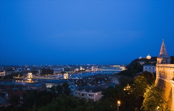 Buda Castle District view over Danube and Pest from Fishermen's Bastion with Memorial Chain Bridge illuminated.