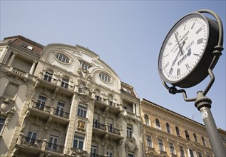 Clock with Art Nouveau facade behind in central Pest.