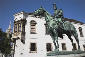 Buda Castle District: Bronze statue of mounted Hussar with Matyas Church tower behind.