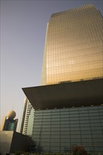 Curved glass facade of National Bank of Dubai building with Etisalat tower behind
