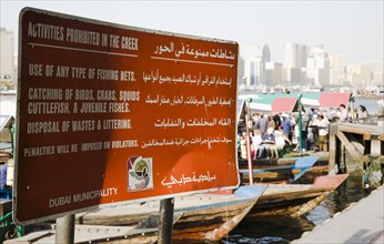 Municipal sign showing rules and penalties on the Creek with skyline behind.