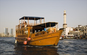 restored traditional boat taking tourists on the Creek with Twin Towers shopping mall and skyline behind.